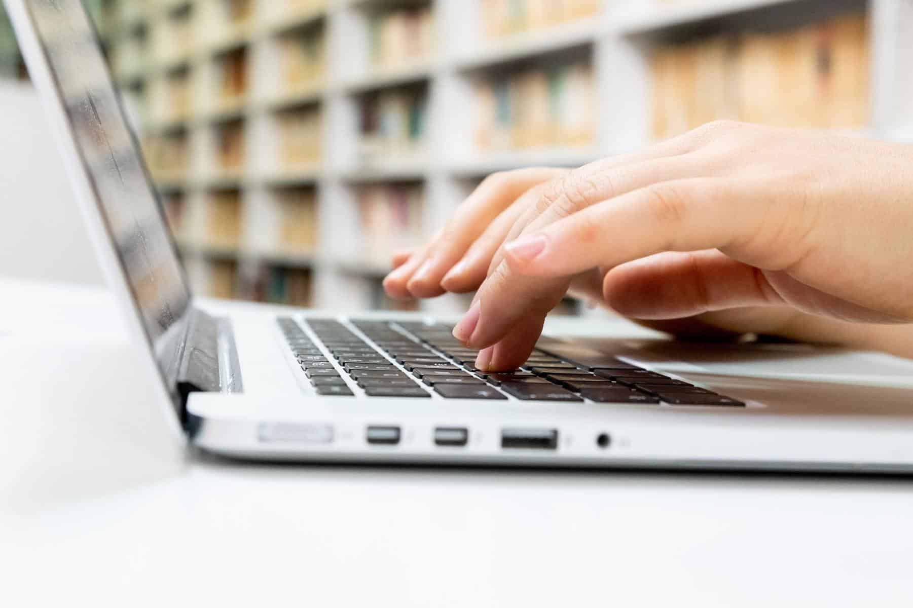 Person typing on white laptop