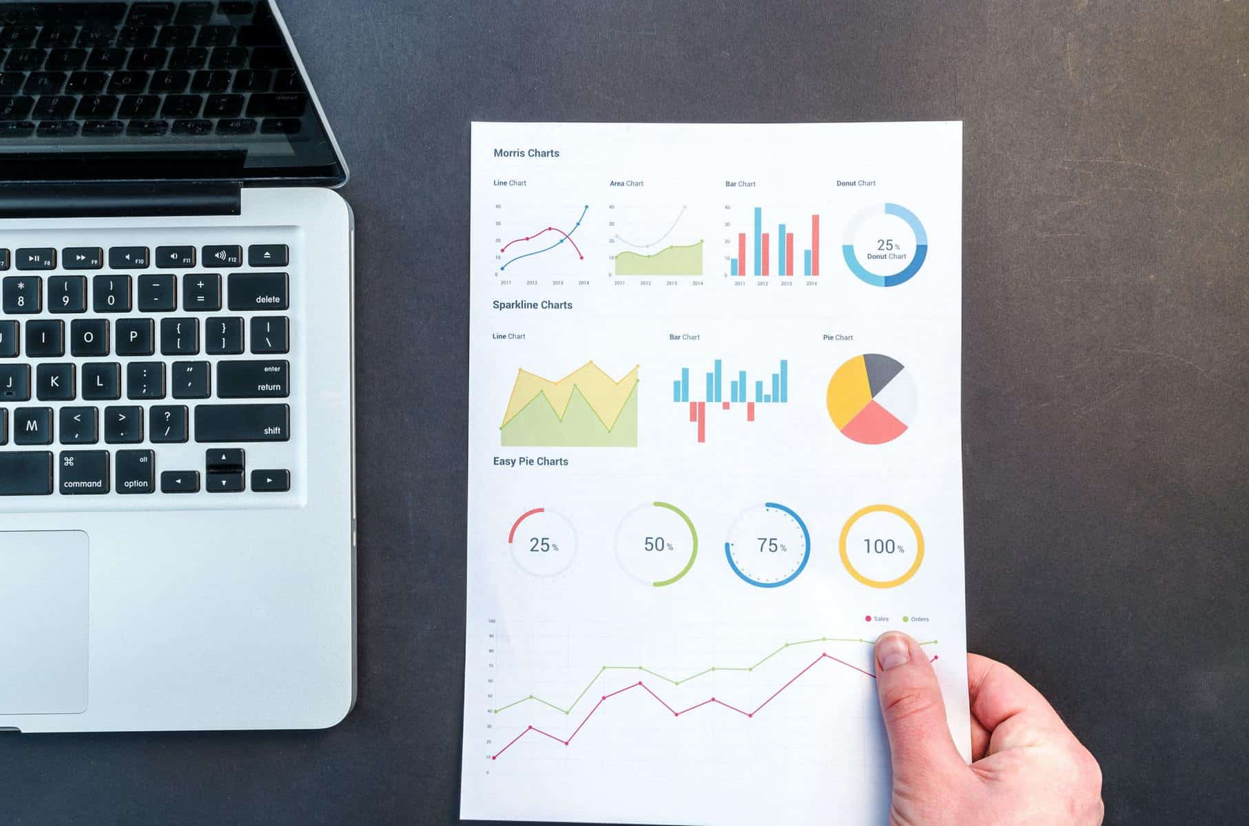 Person holding chart next to laptop