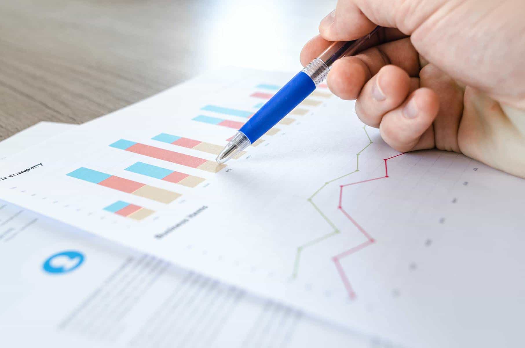 Person pointing pen at printed chart